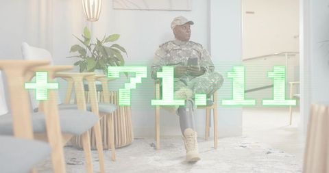 Veteran soldier sitting in clinic waiting room wearing prosthetic leg and holding phone