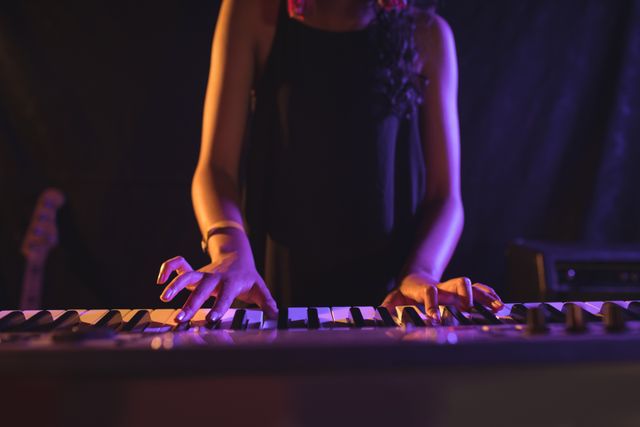 Mid section of female musician playing piano while performing in nightclub