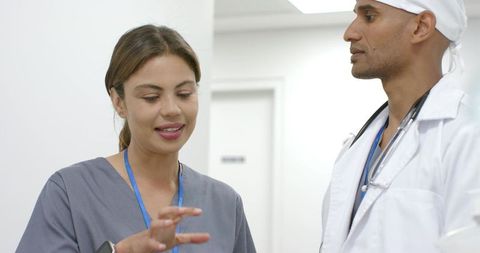 African american doctor and nurse discussing patient case in clinic corridor collaborating