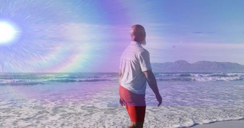 Man Strolling Beach in Sunlight Beside Ocean Waves