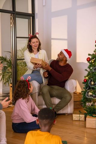Diverse family celebrating christmas together exchanging gifts
