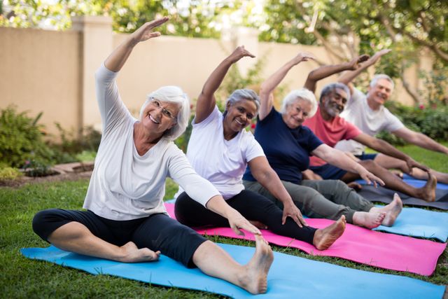 Group of senior friends engaging in outdoor exercise on yoga mats in a park. They are stretching and smiling, promoting a healthy and active lifestyle. Ideal for use in health and wellness campaigns, senior fitness programs, community activities, and retirement living promotions.