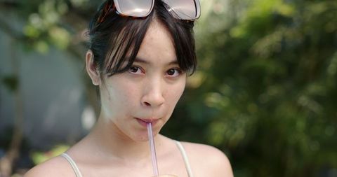 Asian woman enjoying refreshing iced beverage on sunny day