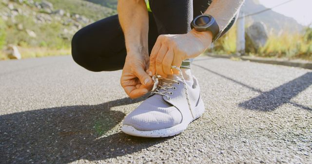 Caucasian woman ties her shoe outdoors, with copy space. Morning light enhances the healthy lifestyle theme as she prepares for a run.
