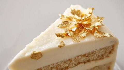 Elegant vanilla layer cake slice with gold leaf decoration and smooth creamy frosting