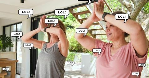 Two women exercising on sunny veranda overlooking garden raising arms with lol stickers