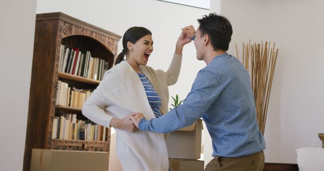 Young couple expressing joy and excitement after moving into their new home. Boxes and personal items are seen around, conveying a fresh new start. This image is ideal for advertisements related to real estate, moving services, or home decoration. It captures the emotions associated with transitioning into a new chapter of life.