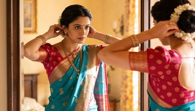 Adjusting earrings pre-wedding indian woman wearing turquoise silk saree and gold jewelry