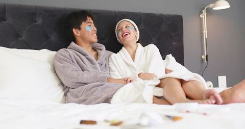 Couple enjoying at-home spa morning wearing blue under-eye patches and plush robes, smiling