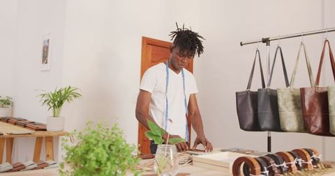 African american craftsman arranging products in leather workshop