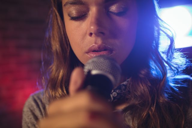 This image captures a close-up view of a female singer performing passionately on stage. Ideal for use in music-related promotions, concert advertisements, artist profiles, and entertainment industry content.
