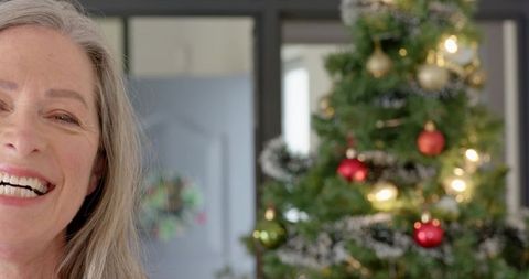 Joyful Senior Woman Smiling by Decorated Christmas Tree