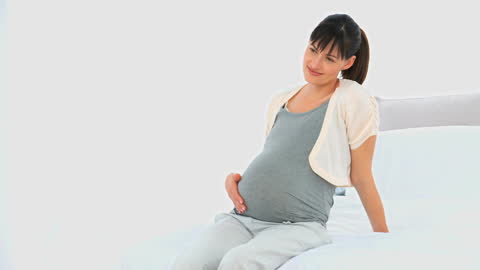 Pregnant Woman Relaxing on Bed with Gentle Smile