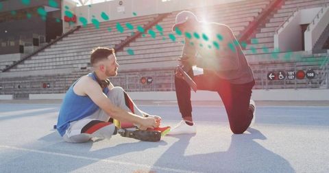 Coach adjusting prosthetic runner on stadium track during sunlit training session