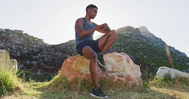 Man in Athletic Wear Checking Fitness Watch While Resting on Rock - Download Free Stock Images Pikwizard.com