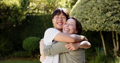 Joyful mother and son hugging in sunlit garden