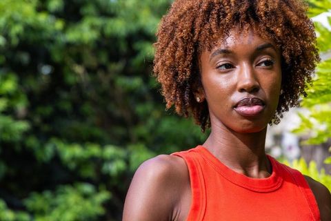 Confident african american woman posing outdoors in red tank top with natural curly hair