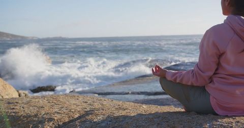 Woman Meditating by Ocean Rocks with Sunrise Waves for Tranquility