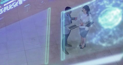 Business colleagues collaborating with laptop and tablet under holographic projection