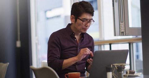 Businessman Efficiently Multitasking at Modern Cafe with Technology