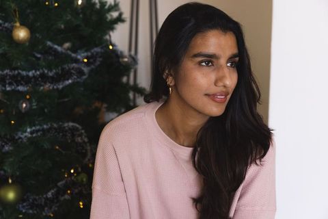 Thoughtful South Asian Woman by Christmas Tree in Cozy Home