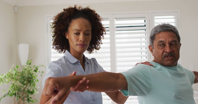Biracial female physiotherapist helping senior man stretching his arms - Download Free Stock Photos Pikwizard.com