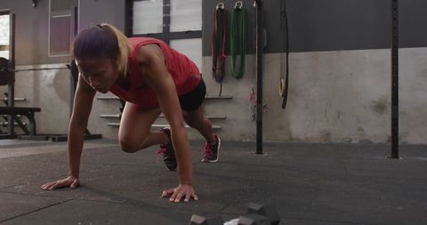 Athletic woman performing intense mountain climbers in urban gym