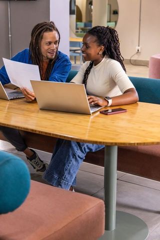 Diverse coworkers collaborating at modern coworking space with laptops and paperwork