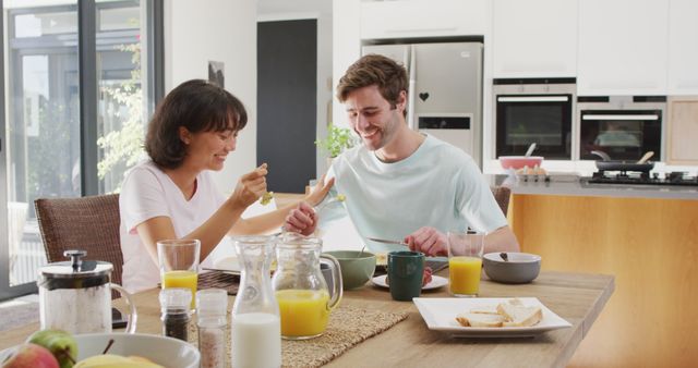 Image of happy diverse couple eating breakfast together in kitchen. Love, relationship and spending quality time together concept.