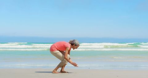 Senior Woman Collecting Seashells on Tranquil Beach - Download Free Stock Images Pikwizard.com