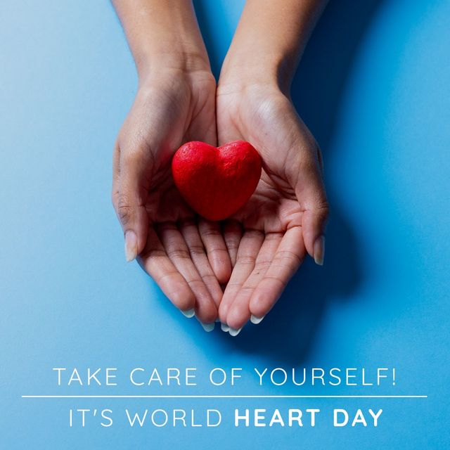 World heart day text banner with red heart in cupped hands against blue background. World heart day awareness concept
