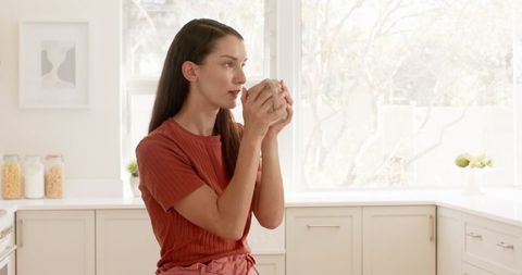 Woman Drinking Coffee in Minimalist Kitchen with Natural Light