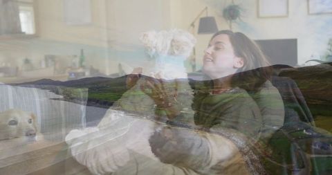 Woman cuddling small white dog on couch layered with rolling green hills for cozy escape