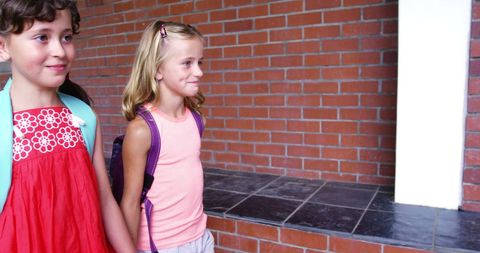Schoolgirls Holding Hands Walking Together in Hallway
