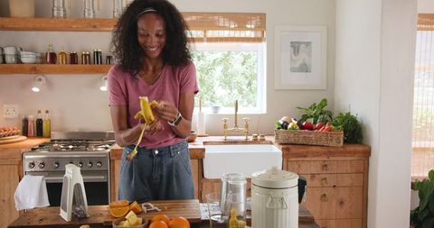 Joyful Woman Preparing Fresh Fruit Smoothie at Home