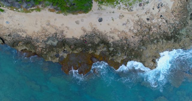 Drone view of caucasian couple sitting on beach in coastline with copy space. Exploration, travel, coast, vacations and nature, unaltered.