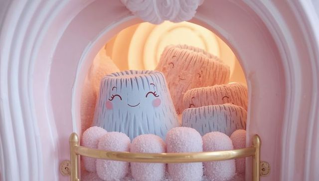 Pastel kawaii plush stumps nestled in pink niche with pom-pom cushion and gold railing