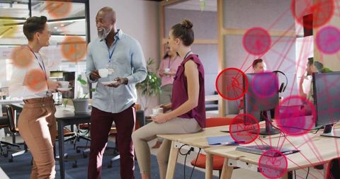 Colleagues chatting over coffee in modern open office lounge with collaborative workstations