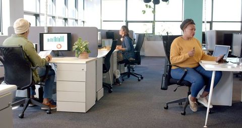 Diverse team collaborating in modern open-plan office with laptop, tablet and data charts