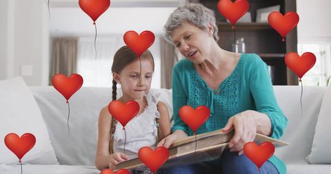 Grandmother Reading to Granddaughter Surrounded by Heart Balloons