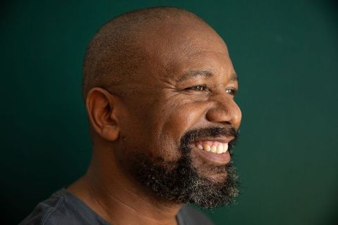 African american mature man smiling in profile on green backdrop showing confidence