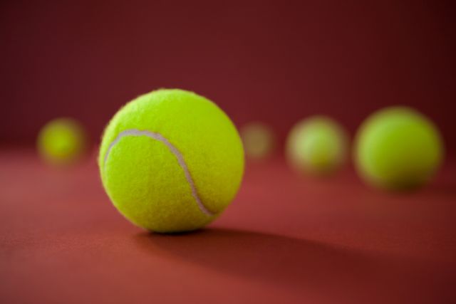 Close up of fluorescent yellow tennis balls on maroon background