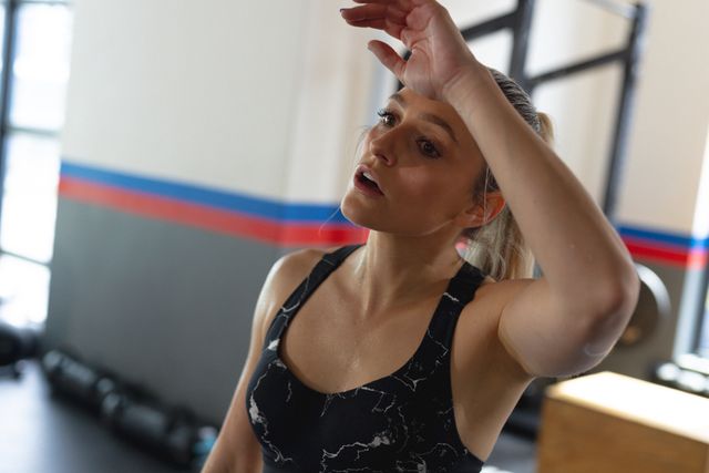 Photo of caucasian fit woman wiping her forehead, exercising in gym. Fitness, health, active lifestyle and sport concept.