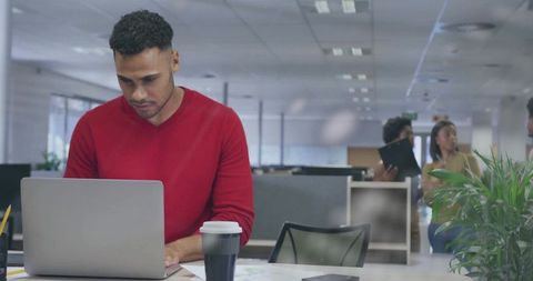 Focused Professional Man Typing at Laptop in Open-Plan Office