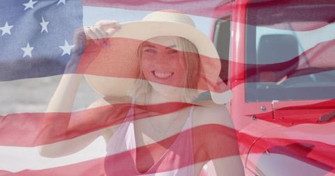 Smiling woman in sun hat holding brim at beach with red jeep and american flag overlay