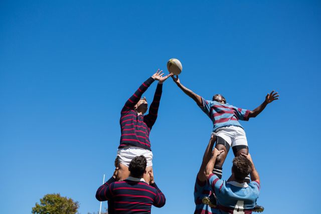 Rugby players are competing for the ball in mid-air, showcasing athleticism and teamwork. This image can be used for sports-related articles, advertisements, or promotional materials highlighting the intensity and spirit of rugby. Ideal for websites, magazines, and social media posts focusing on sports, fitness, and team activities.