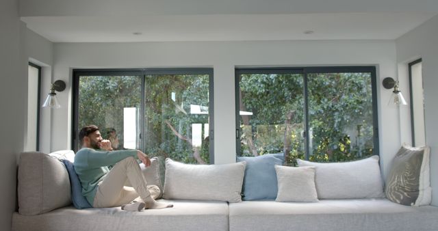 Man Relaxing on Cozy Sofa by Window at Home - Download Free Stock Images Pikwizard.com