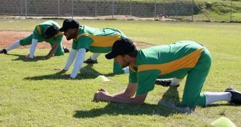 Baseball Team Stretching on Sunny Field in Green and Yellow Uniforms