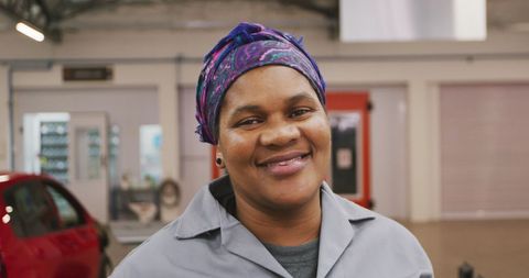 Smiling Mechanic in Workshop with Car and Tools