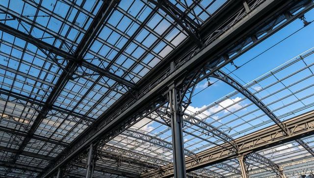 Glass-and-steel station roof featuring exposed trusses, canopy grid, industrial geometry